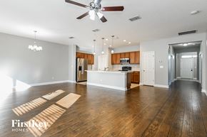 Jacksonville house for rent - an empty living room with a kitchen and a ceiling fan
