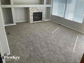 Commerce City house for rent - a living room with a fireplace and a carpeted floor