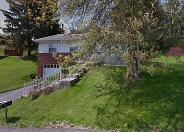 Pittsburgh house for rent - A house with a red brick chimney is surrounded by a green lawn and trees.
