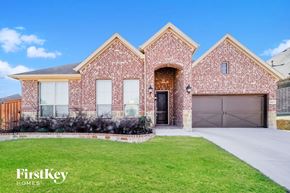Aledo house for rent - a brick house with a garage door and a lawn