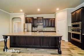 Aledo house for rent - a kitchen with dark wood cabinets and a marble counter top