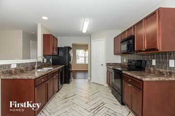 Kernersville house for rent - A kitchen with brown cabinets and a black refrigerator.
