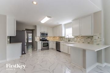 Tomball house for rent - a large kitchen with white cabinets and marble flooring