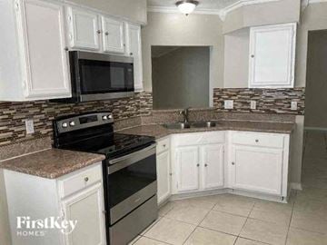 Jacksonville house for rent - A kitchen with a black stove top oven and a black microwave above a counter with a granite counter top.