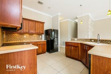 Lehigh Acres house for rent - a kitchen with wooden cabinets and a black refrigerator