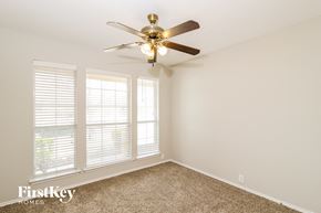 Crossroads house for rent - a bedroom with a ceiling fan and three windows