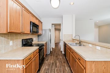 Crossroads house for rent - a kitchen with wooden cabinets and a black stove and a sink
