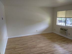 Davis apartment for rent - an empty living room with wooden floors and a window