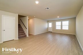 Bulverde house for rent - A spacious room with wooden flooring and a staircase leading to another room.