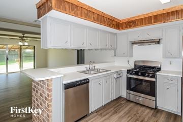 Spring house for rent - A kitchen with white cabinets and a wooden ceiling.