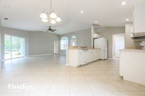 Rotonda West house for rent - an open kitchen and living room with white cabinets and tile floors