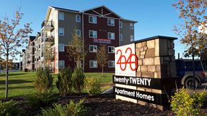 Red Deer apartment for rent - A sign for Twenty Twenty Apartment Homes in front of a building.