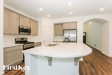 Iowa Colony house for rent - A kitchen with a white counter top and wooden cabinets.