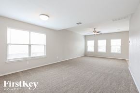 San Antonio house for rent - A spacious room with a carpeted floor, a ceiling fan, and three windows.