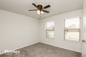 Fort Worth house for rent - a bedroom with a ceiling fan and two windows