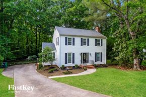 Charlotte house for rent - a white house with green trees and a driveway