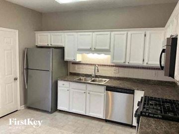 Hiram house for rent - a kitchen with white cabinets and a stainless steel refrigerator