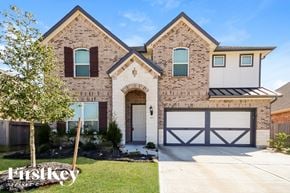 Katy house for rent - A brick house with a garage door that is half open.