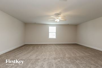 Clarksville house for rent - a spacious living room with carpet and a ceiling fan