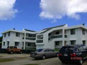 Mongmong-Toto-Maite apartment for rent - a white apartment building with cars parked in front of it