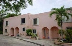Sinajana apartment for rent - a pink building with palm trees in front of it