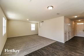 Jacksonville house for rent - A spacious room with wooden floors and white walls, with a carpet on the floor and a door on the right side.
