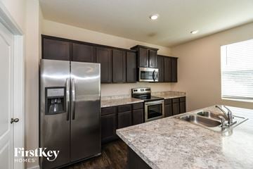 Jacksonville house for rent - A kitchen with a stainless steel refrigerator and dark brown cabinets.