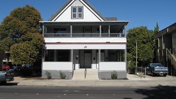 Stockton apartment for rent - A white two-story house with a grey roof and a black car parked in front.