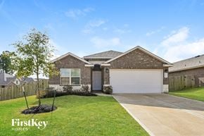 Conroe house for rent - a brick house with a white garage door and a lawn