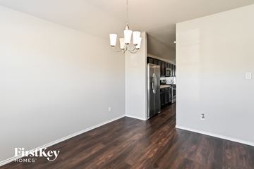 Conroe house for rent - the living room and kitchen of an apartment with wood flooring and a refrigerator