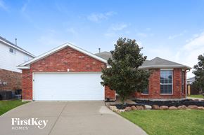 Forney house for rent - A brick house with a white garage door and a tree in front.