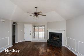 Forney house for rent - A room with a fireplace and a ceiling fan.