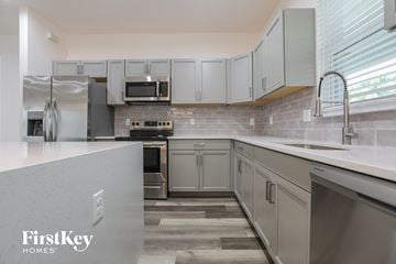 North Port house for rent - a modern kitchen with white cabinets and stainless steel appliances