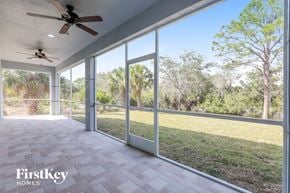 North Port house for rent - a patio with sliding glass doors and a grass field
