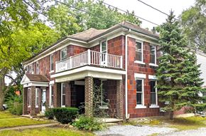 Hobart apartment for rent - a red brick house with a balcony and a tree