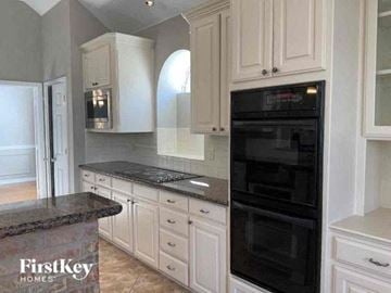 Arlington house for rent - a kitchen with white cabinets and a black oven