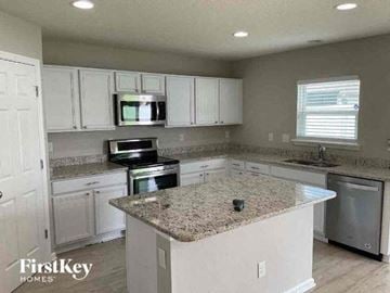 Middleburg house for rent - a kitchen with white cabinets and a granite counter top