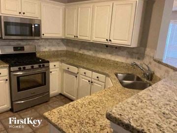 Kennesaw house for rent - a kitchen with white cabinets and granite counter tops