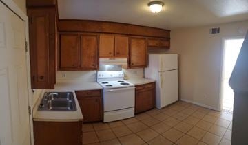Hattiesburg apartment for rent - A kitchen with wooden cabinets and white appliances.
