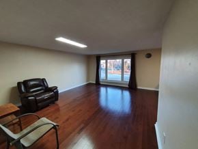 Toronto house for rent - A living room with a black leather chair and a wooden floor.