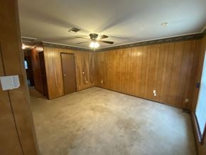 Hattiesburg house for rent - a living room with wood paneling and a ceiling fan
