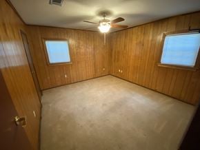 Hattiesburg house for rent - an empty room with a ceiling fan and two windows