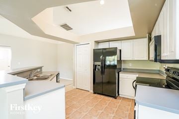Cape Coral house for rent - a kitchen with white cabinets and a stainless steel refrigerator