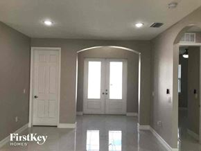 Lehigh Acres house for rent - A spacious room with a white door and a large arched window.