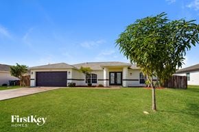 Cape Coral house for rent - a house with a green lawn and a tree