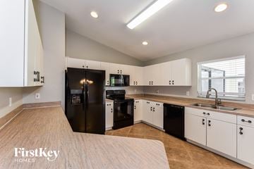 Cape Coral house for rent - a large kitchen with black appliances and white cabinets
