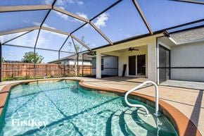 Cape Coral house for rent - a swimming pool in a house with a patio and a pool enclosure