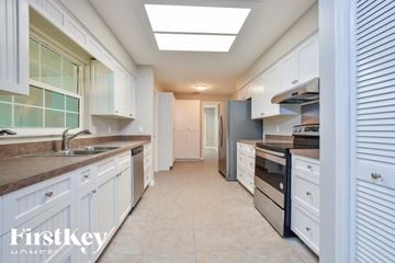 Deltona house for rent - A kitchen with white cabinets and a tiled backsplash.