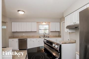 Rockledge house for rent - A kitchen with a stove top oven and white cabinets.