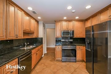 Jacksonville house for rent - a kitchen with wood cabinets and black counter tops and black appliances